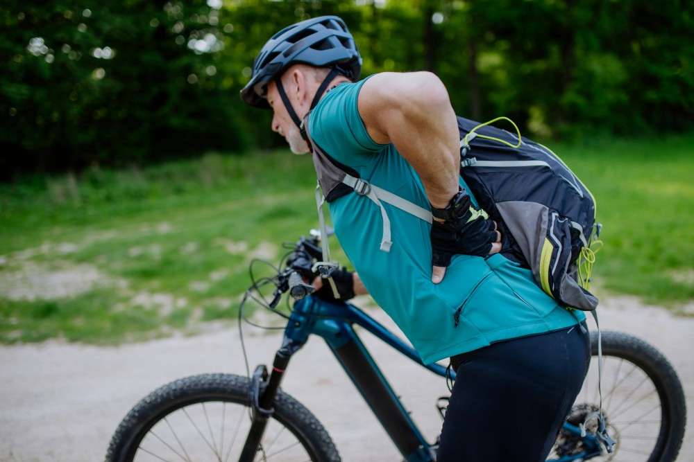 Présentation d'un cycliste en crise de lumbago se demandant quelle est la cause et quel sera le traitement de sa lombalgie