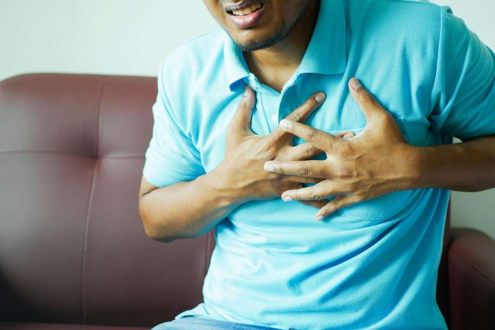 Vue d'un homme se tenant la poitrine pour douleur thoracique et syndrome de Tietze