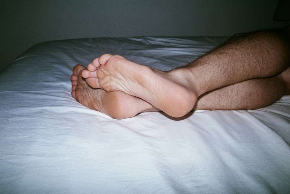 Présentation pieds et jambes d'un homme fatigué par sommeil altéré car il souffre du syndrome des jambes sans repos