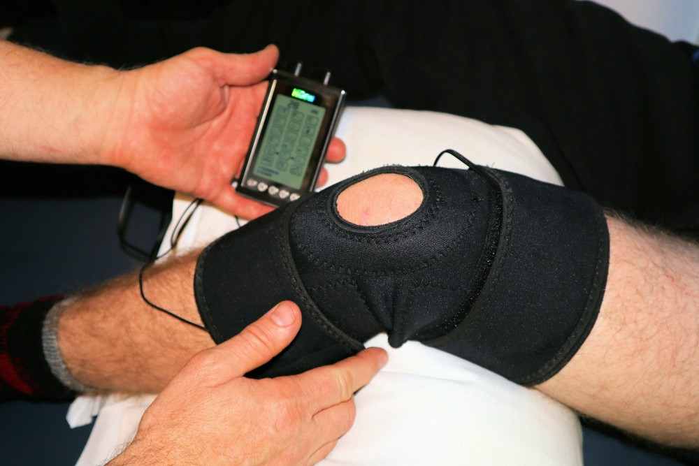 Homme avec tendinite du genou avec attelle et appareil tens contre la douleur