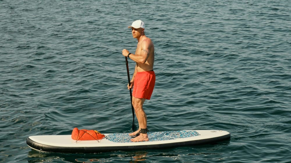 Homme avec une casquette faisant du stand up paddle gonflable