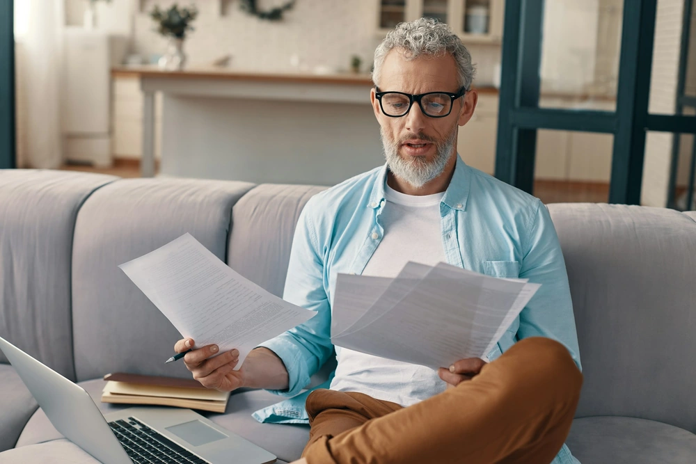 Homme comparant ses documents de complémentaire santé pour le remboursement chiropracteur