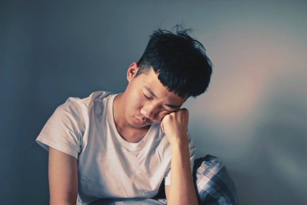 Jeune homme asiatique qui dort posé sur sa main